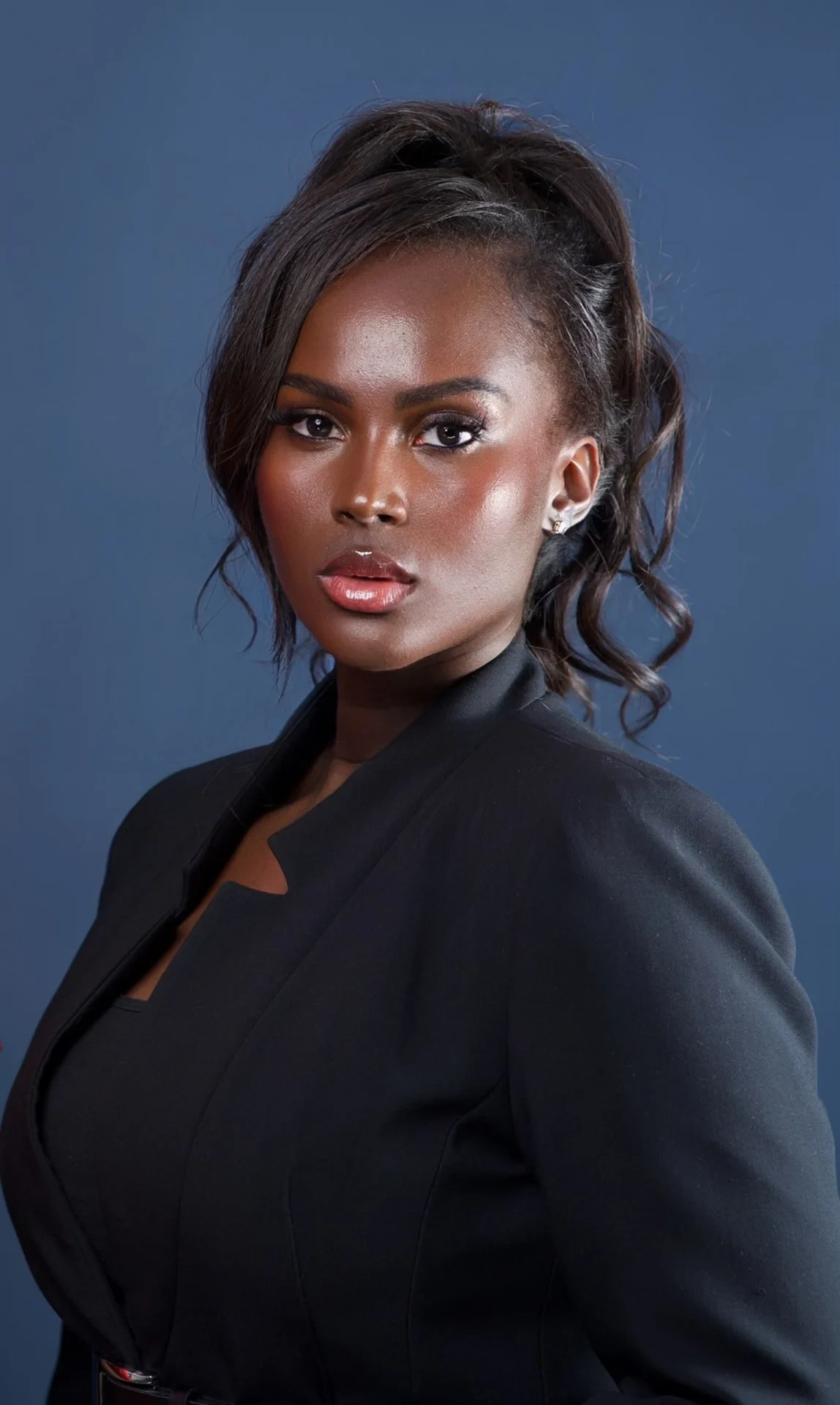 Portrait de Marie Paula Sylva, autrice sénégalaise, en veste noire sur fond bleu